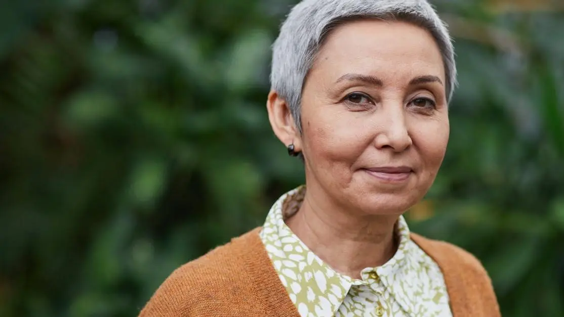 Joyful senior Asian woman outdoors, symbolizing confidence with permanent dentures.