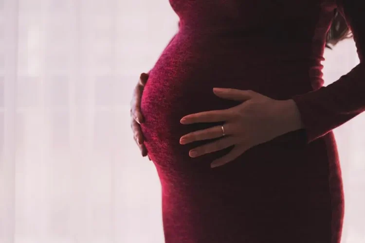 Pregnant woman holding belly, highlighting pregnancy oral health impact.