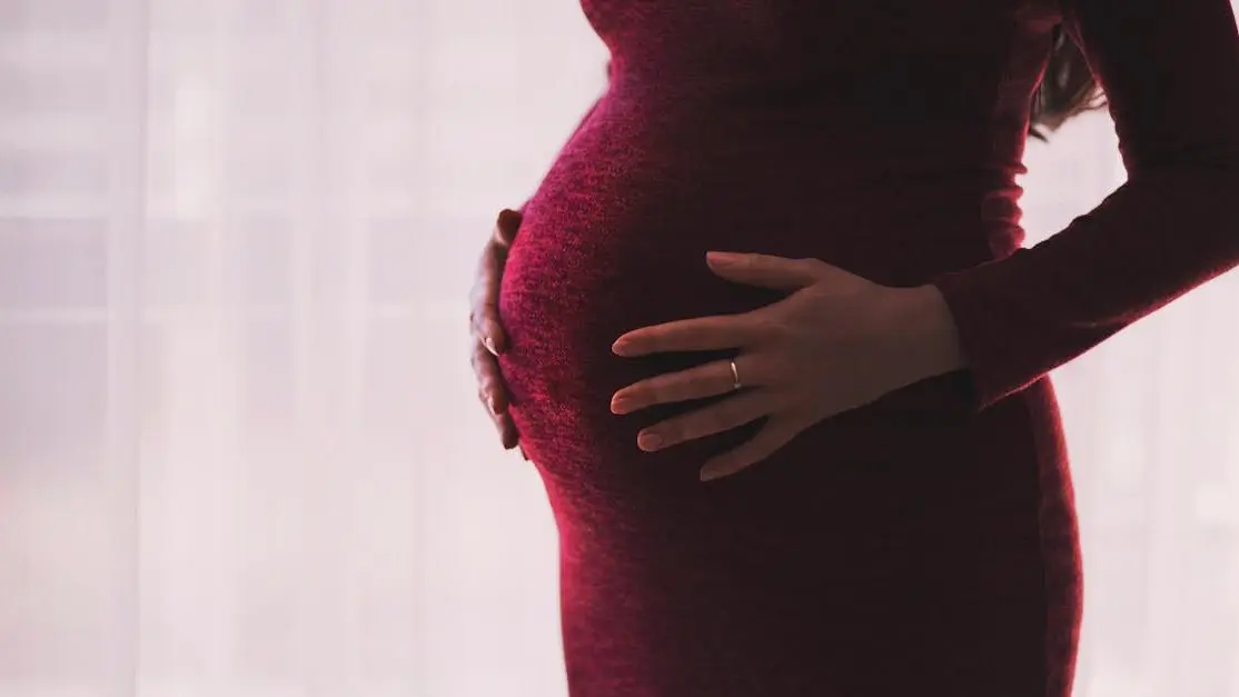 Pregnant woman holding belly, highlighting pregnancy oral health impact.