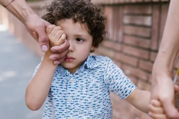 Child holding hands with family, symbolizing preparing your child for their first dental visit.