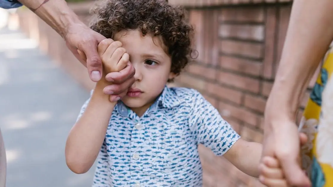 Child holding hands with family, symbolizing preparing your child for their first dental visit.