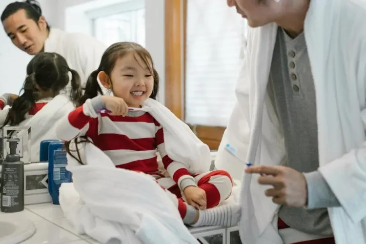 Father and daughter practicing preventive dental care for families in a cozy bathroom.