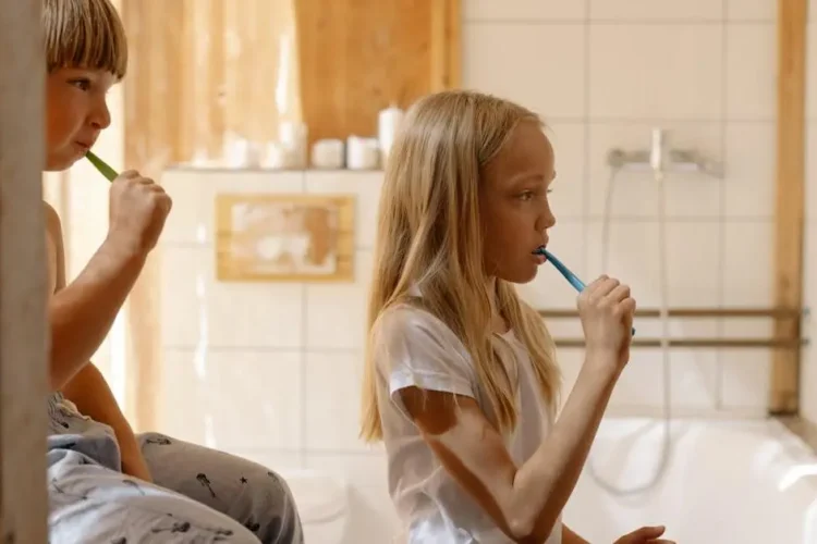 Children practicing oral care in a bright bathroom, illustrating professional vs. at-home teeth whitening.