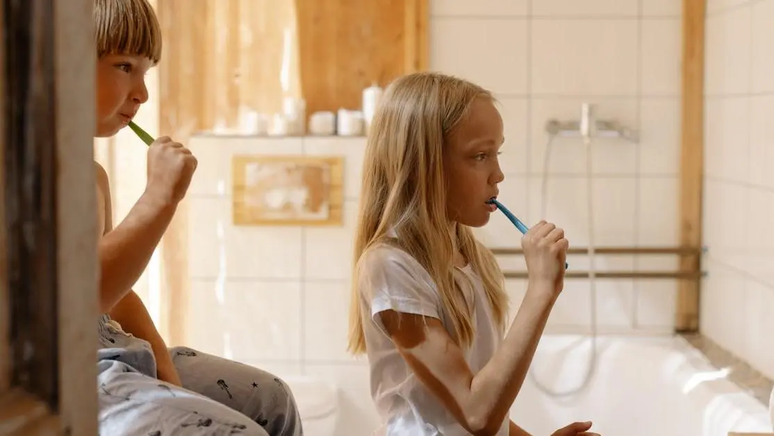 Children practicing oral care in a bright bathroom, illustrating professional vs. at-home teeth whitening.