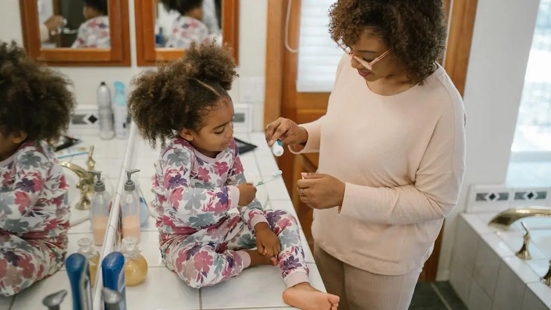 Child brushing teeth under mother's supervision, illustrating sugar impact on children's teeth.