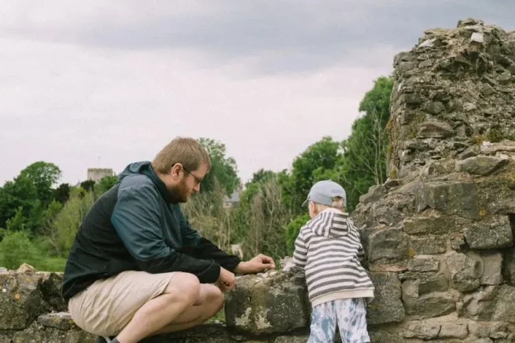 Man and child exploring ancient stone ruins, illustrating the tell show do method in learning.