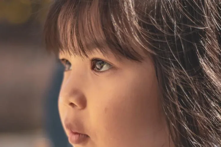 Young girl with brown eyes demonstrating tongue thrusting.